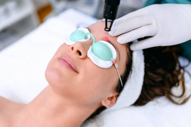 Close-up of a female cosmetologist in a medical coat making a young woman a procedure laser hair removal for the face. Cosmetology, ionization, diamond procedures.